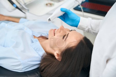 Téléchargez les photos : Dentiste professionnel vérifiant la santé buccale du client féminin avec caméra intra-buccale dentaire, pour mieux voir toute l'inflammation, les caries et la carie - en image libre de droit
