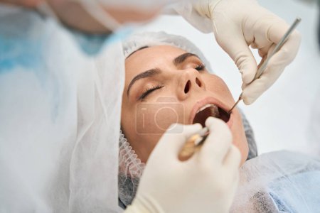 Foto de Médico en una clínica dental moderna limpia los canales dentales de una mujer joven, el dentista utiliza herramientas especiales - Imagen libre de derechos
