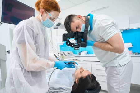 Foto de Paciente femenina en la recepción en el consultorio dental, médico con ayuda de asistente fotografía sus dientes con una cámara - Imagen libre de derechos