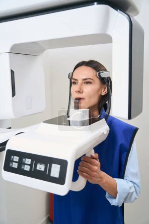 Foto de Paciente joven está en un procedimiento de escaneo 3D, un delantal de protección está en la mujer - Imagen libre de derechos