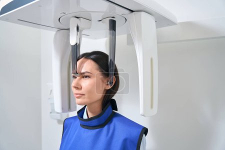 Foto de Mujer morena está en un procedimiento de diagnóstico en una sala de rayos X, un delantal de protección está en el paciente - Imagen libre de derechos