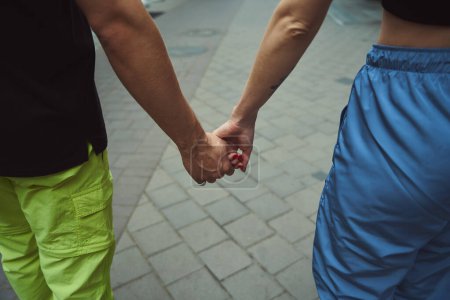 Téléchargez les photos : Vue recadrée du couple caucasien tenant la main les uns des autres tout en marchant dans la rue - en image libre de droit
