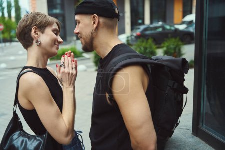 Foto de Mujer alegre con manicura y tatuaje de pie cerca de su novio en la calle moderna - Imagen libre de derechos