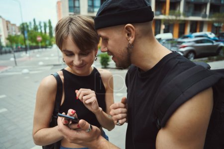 Téléchargez les photos : Blanc homme et femme navigation téléphone cellulaire ensemble tout en se tenant sur la rue moderne - en image libre de droit