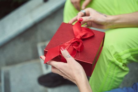 Photo for Cropped view on hands of woman with manicure and tattoos opening gift box from her boyfriend - Royalty Free Image