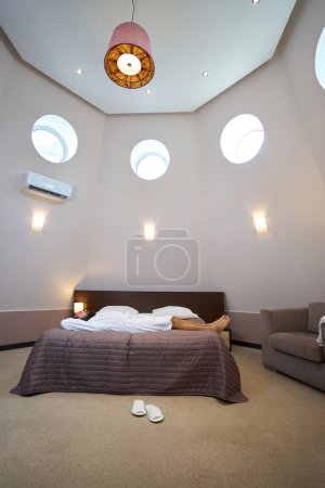 Téléchargez les photos : Hôtel se prélasse sur un grand lit dans une chambre confortable, air conditionné sur le mur - en image libre de droit