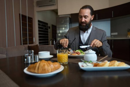 Téléchargez les photos : Le voyageur prend le petit déjeuner à la table dans la chambre d'hôtel, la table est mise pour une personne - en image libre de droit