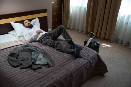 Foto de Viajero solitario acostarse a descansar sobre almohadas suaves, la habitación es limpia y cómoda - Imagen libre de derechos