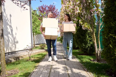 Téléchargez les photos : Homme et femme caucasiens tenant des boîtes et se regardant tout en se tenant dehors - en image libre de droit