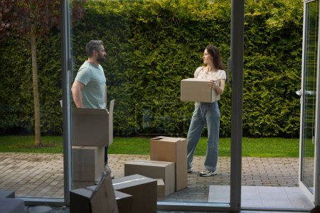 Foto de Hombre joven en ropa casual y mujer con caja de cartón mirando el uno al otro afuera - Imagen libre de derechos
