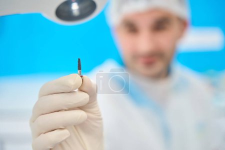 Photo for Doctor holds in his hand a dental pin for prosthetics of the dentition - Royalty Free Image