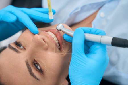 Foto de Técnico dental que va a perforar el diente al cliente femenino, tratando el nervio irritado en la raíz del diente, haciendo terapia de conductos radiculares limpiando los nervios y los vasos sanguíneos - Imagen libre de derechos