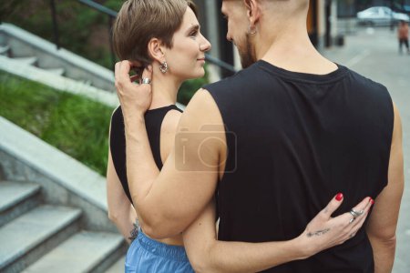 Téléchargez les photos : Les jeunes hommes s'embrassent le long du trottoir dans une grande ville, ils portent des vêtements de jeunesse confortables - en image libre de droit