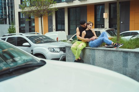 Téléchargez les photos : Couple amoureux repose sur un parapet haut, un gars étreint sa petite amie, parking à proximité - en image libre de droit