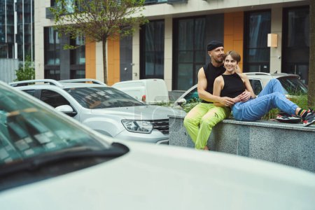 Foto de Pareja en el amor está descansando en un paseo por la ciudad, el tipo abraza a su novia, aparcamiento cercano - Imagen libre de derechos