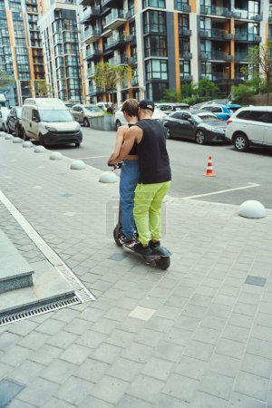 Foto de Los jóvenes se mueven por la ciudad en un scooter, montan en la acera - Imagen libre de derechos