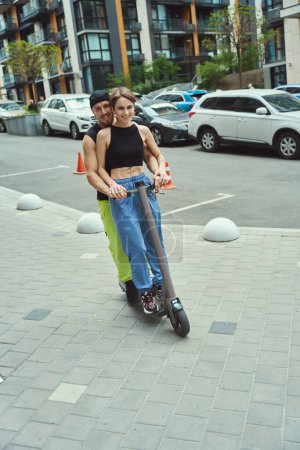Photo for Guy with a girlfriend move around the city on a scooter, they ride along the sidewalk - Royalty Free Image