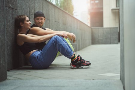 Téléchargez les photos : Jolie jeune femme et son amie informelle bavardent assis sur le trottoir dans une petite cour dans une métropole - en image libre de droit