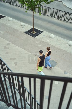 Téléchargez les photos : Les jeunes marchent le long du trottoir, se tenant la main, ils ont des sacs à provisions - en image libre de droit