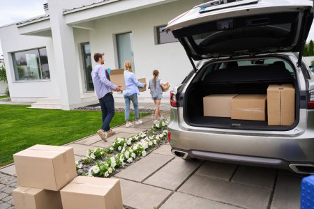 Photo for Parents with a teenage daughter move to a new modern house, people carry cardboard boxes with things - Royalty Free Image