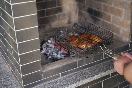 Téléchargez les photos : Homme frites viande sur les charbons sur un gril spécial, il est situé dans la zone des branchies - en image libre de droit