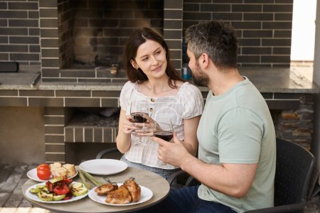 Téléchargez les photos : Couple d'âge moyen dîner sur la viande et le vin dans la cour, le couple est situé dans la zone de grill - en image libre de droit