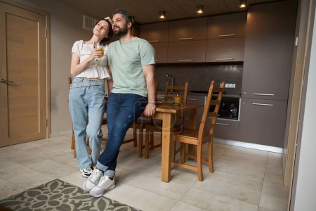 Téléchargez les photos : Blanc homme et femme se sont installés à la maison dans la cuisine, mâle étreint sa femme - en image libre de droit