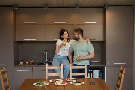 Téléchargez les photos : Mignonnes épouses sont à la maison dans la cuisine, le petit déjeuner est servi sur une table en bois - en image libre de droit