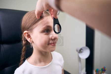Photo for Doctor in the clinic checks the eyesight of a young patient, the ophthalmologist uses a special tool - Royalty Free Image