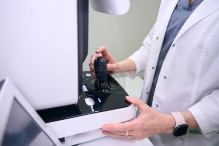 Téléchargez les photos : Ophtalmologiste spécialiste sur le lieu de travail utilise un équipement moderne, médecin en robe médicale - en image libre de droit
