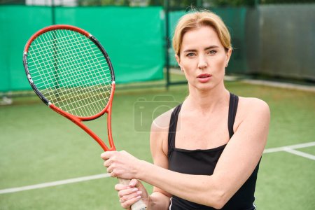 Foto de Enfocada hermosa hembra en la cancha de tenis, ella tiene una raqueta de tenis en sus manos - Imagen libre de derechos