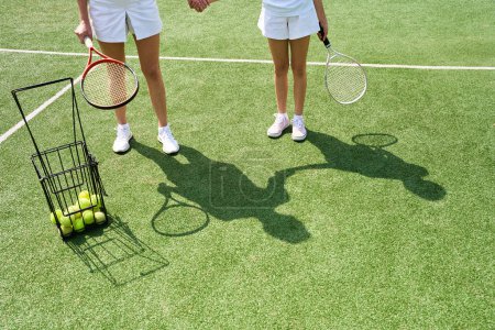 Photo for Young woman and a girl are on the tennis court, the female is holding the childs hand - Royalty Free Image