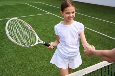 Foto de Joven tenista toma la pelota de las manos de una mujer joven, chica tiene raqueta de tenis en sus manos - Imagen libre de derechos