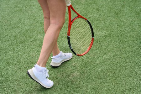 Foto de Mujer con hermosas piernas camina a lo largo de la pista de tenis, ella tiene una raqueta de tenis en sus manos - Imagen libre de derechos
