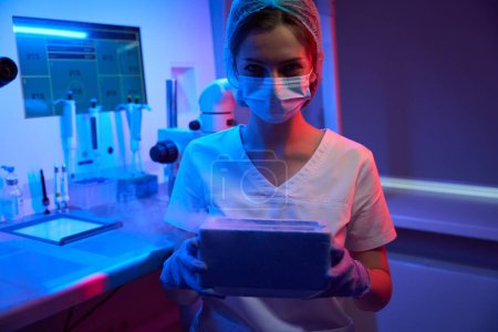 Photo for Embryologist laboratory assistant holds a tank with liquid nitrogen in her hands for cryopreservation of biological material - Royalty Free Image
