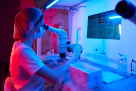 Foto de Embriólogo joven en el trabajo en un crio-laboratorio, sobre la mesa un tanque con nitrógeno líquido - Imagen libre de derechos