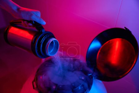 Photo for Laboratory assistant pours liquid nitrogen into the cryocapsule, she uses modern equipment for cryopreservation of the biomaterial - Royalty Free Image