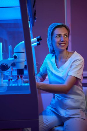 Photo for Young woman in the workplace in a cryo laboratory, on the table with a powerful microscope - Royalty Free Image