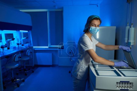 Foto de Mujer con uniforme médico envía un contenedor con un biompterial a una criocámara, se mantienen condiciones óptimas - Imagen libre de derechos