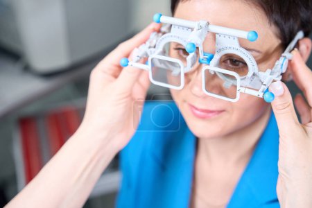 Foto de Manos optometristas poniendo marco de lente de prueba con filtros polarizantes en la cara de la mujer - Imagen libre de derechos