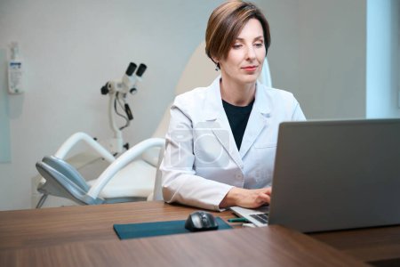Téléchargez les photos : Docteur sur le lieu de travail dans un cabinet gynécologique dans un centre médical, elle utilise un ordinateur portable dans son travail - en image libre de droit