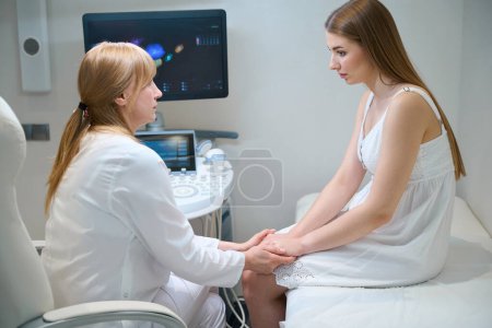 Photo for Female doctor is in an ultrasound room with a young patient, the doctor comforts a sad woman - Royalty Free Image