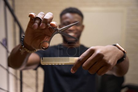 Photo for Hairdresser holds a working tool in his hands, the master has curly hair - Royalty Free Image