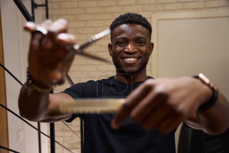 Foto de Peluquería afroamericana está en el lugar de trabajo con tijeras y un peine, esta es su herramienta de trabajo - Imagen libre de derechos