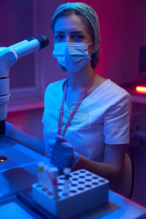 Téléchargez les photos : Jeune embryologue sur le lieu de travail en cryolaboratoire, l'assistante de laboratoire utilise un micromanipulateur et un microscope puissant - en image libre de droit