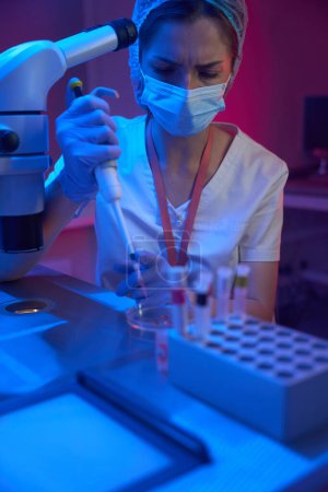 Photo for Young employee of a modern cryo-laboratory works with biomaterial, she uses a special pipette - Royalty Free Image