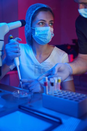 Foto de Joven científica en un crio-laboratorio moderno trabaja con biomaterial, junto a su colega masculino - Imagen libre de derechos