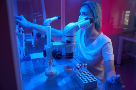 Foto de La científica trabaja en un laboratorio moderno, usa mesas médicas especiales. - Imagen libre de derechos