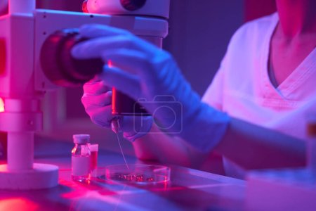 Foto de Embriólogo en un criolab realiza un procedimiento ICSI, tubos de ensayo con biomaterial están sobre la mesa - Imagen libre de derechos