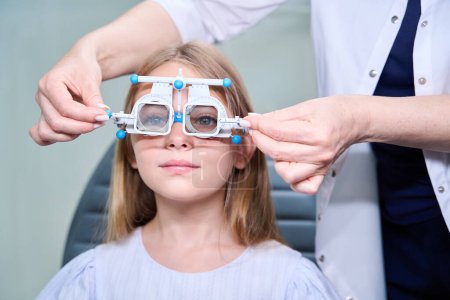 Foto de Optometrista usando marco de prueba oftálmica con filtros polarizantes en niña tranquila - Imagen libre de derechos